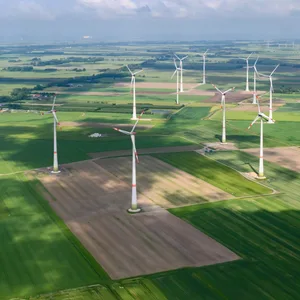 Zahlreiche Windräder stehen auf Feldern zwischen Häusern, Ortschaften und Waldstücken.