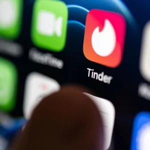 Eine Hand tippt auf die Tinder-App, die auf einem Smartphone installiert ist. (Illustration)