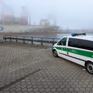 Ein Einsatzfahrzeug des Zolls steht gegenüber dem im Nebel liegenden Containerterminal Tollerort.
