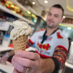 Thomas Micolino, Inhaber des Eiscafé Rino, zeigt ein Eis, das zum Teil aus Grillenmehl besteht und auf dem ein getrocknetes Heimchen sitzt