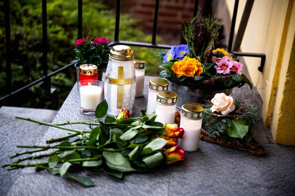 Blumen und Kerzen liegen am Tatort vor einer Grundschule in Bramsche, wo ein 81-Jähriger einen 16-Jährigen tötete.
