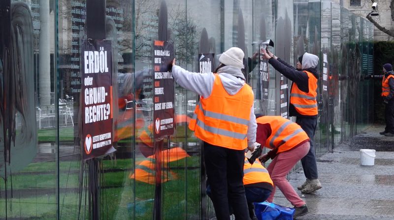 Aktiviste der „Letzten Generation” kleben Plakate an das Denkmal.