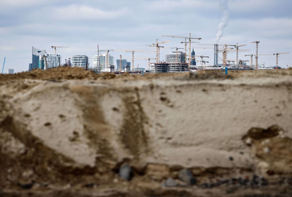 Die Silhouette der Hafencity mit der Elbphilharmonie (l) und ihren zahlreichen Baustellen ist hinter der Sandaufschüttung zur Vorbereitung eines Baufelds auf dem Grasbrook im Hafen zu sehen.