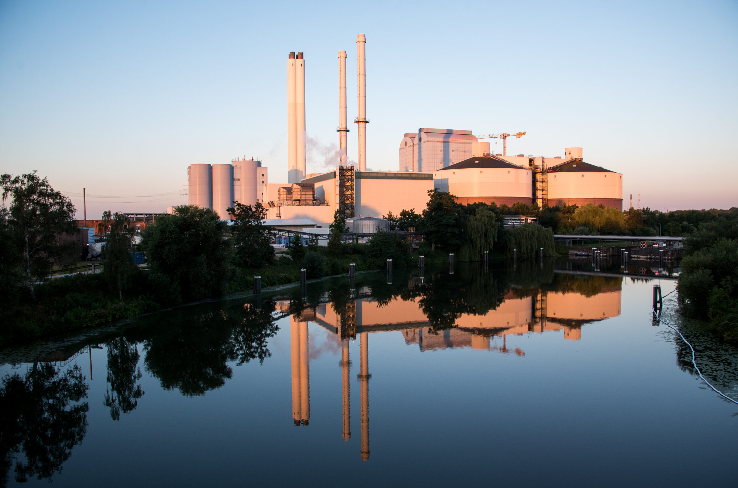 Das Heizkraftwerk Tiefstack spiegelt sich im Morgenlicht im Wasser.