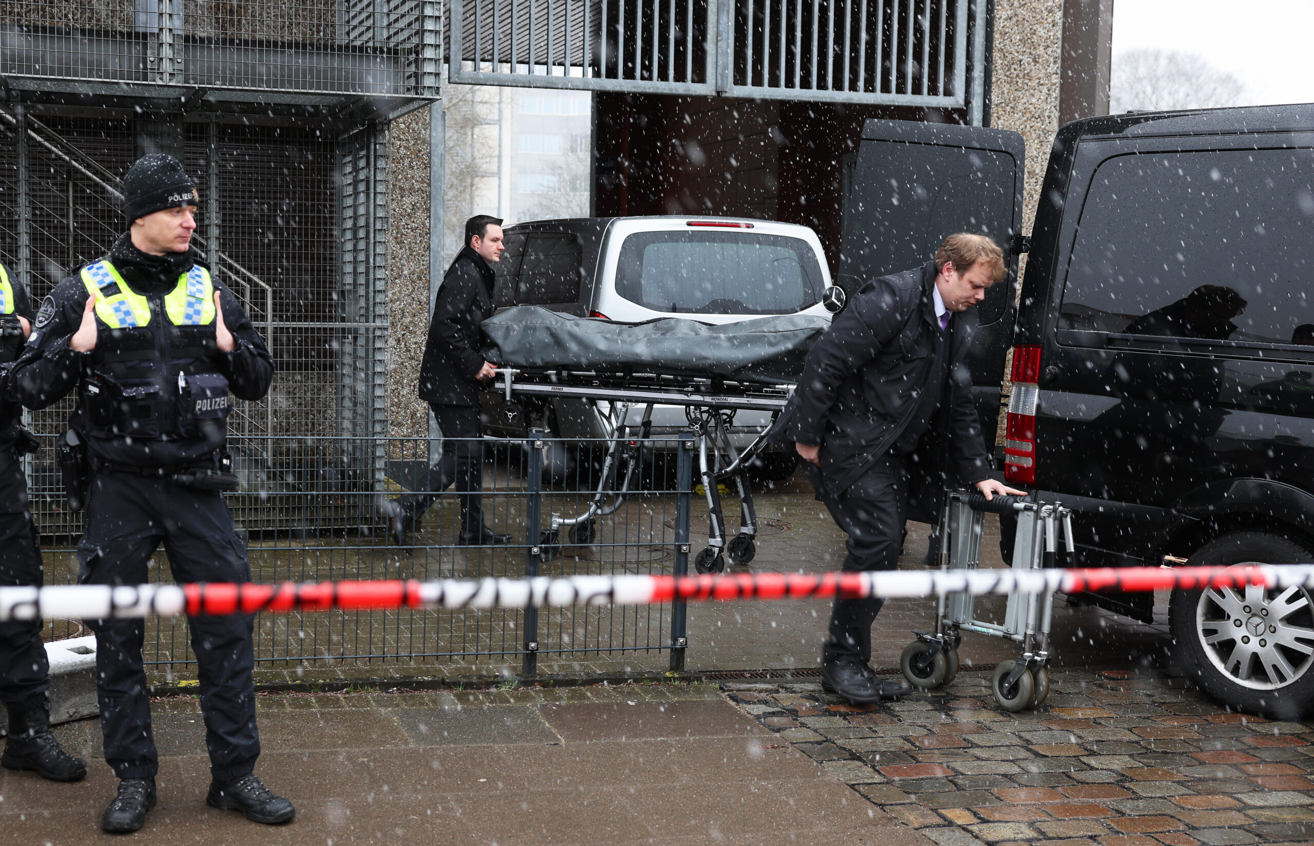 Bestatter bringen eine abgedeckte Bahre zu ihrem Fahrzeug am Gebäude der Zeugen Jehovas im Stadtteil Alsterdorf.