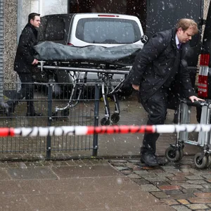 Bestatter bringen eine abgedeckte Bahre zu ihrem Fahrzeug am Gebäude der Zeugen Jehovas im Stadtteil Alsterdorf.