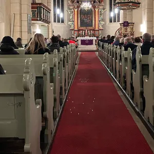 Menschen sitzen bei der Gedenkfeier für die in Bramsche getöteten Verbrechensopfer in der Kirche.