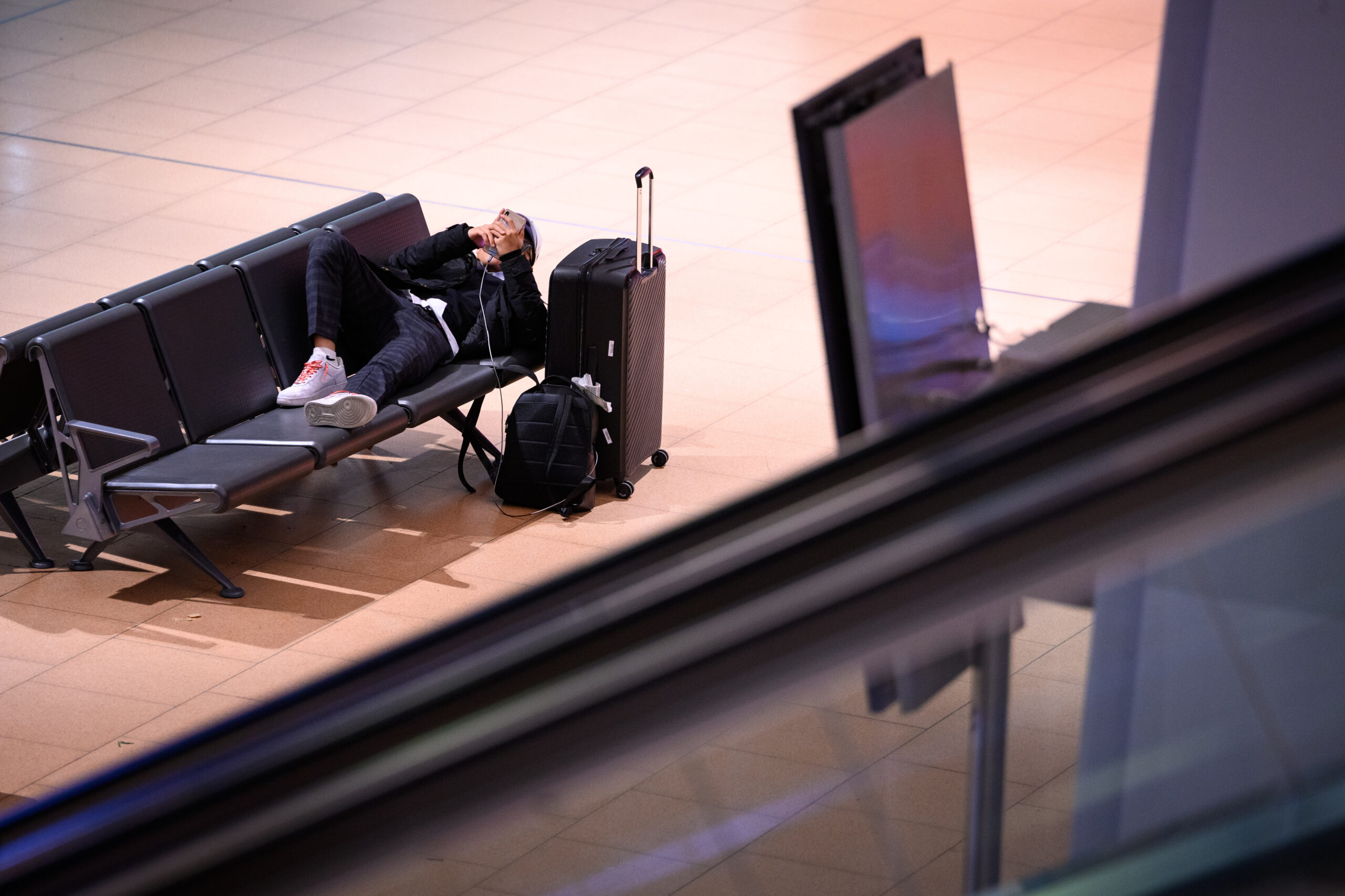 Ein Mann liegt neben seinem Gepäck auf einer Bank am Hamburger Flughafen, der seit Sonntagabend bestreikt wird.