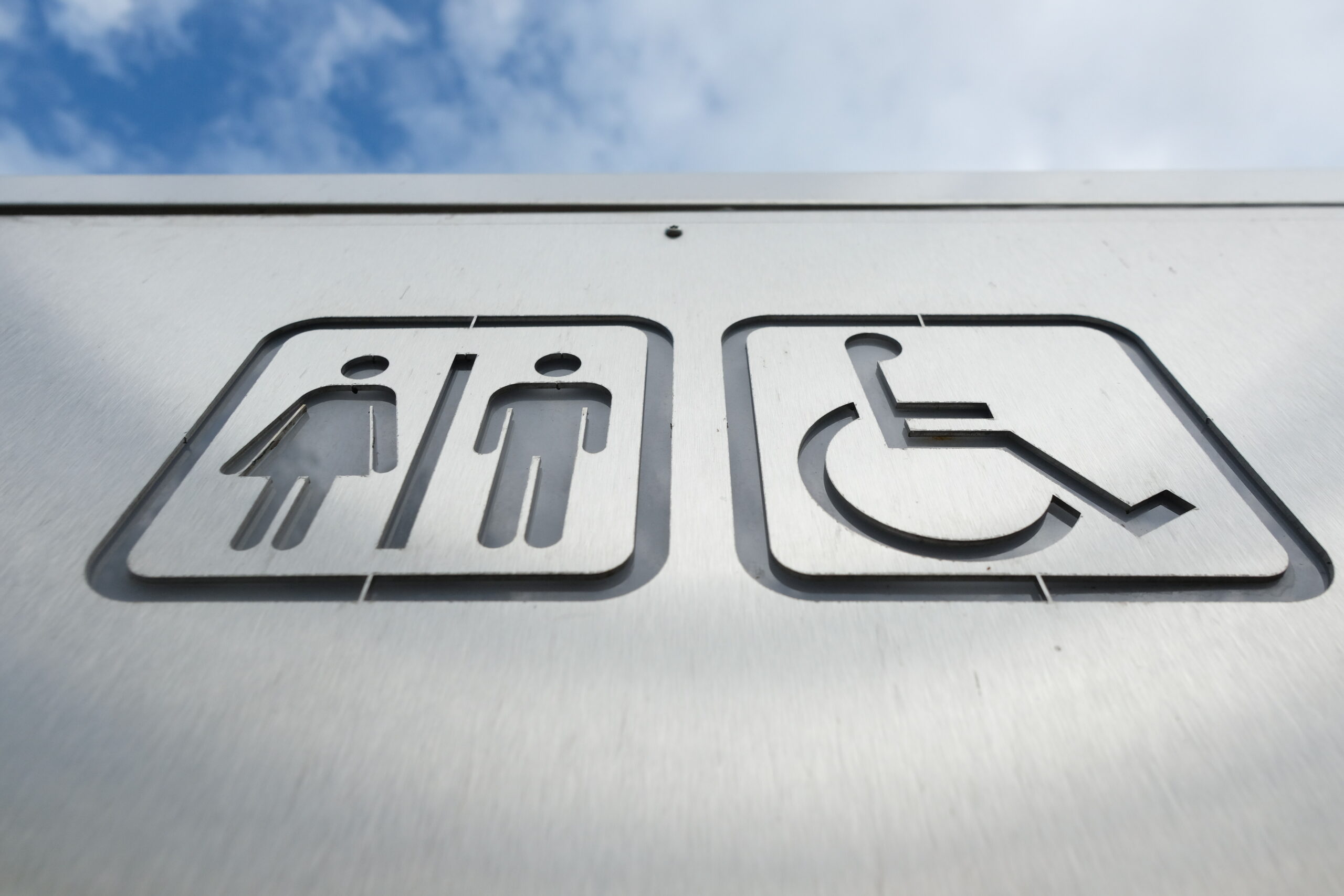 Ein Schild weist den Weg zu einer öffentlichen Toilette - auch für Behinderte.