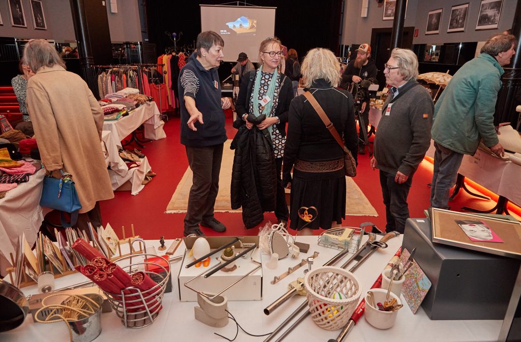 Mitarbeiter von Hamburg Leuchtfeuer und Schnäppchenjäger stehen während eines Benefizverkaufs zwischen verschiedenen Gegenständen in einem Raum im Theater Hamburger Kammerspiele.