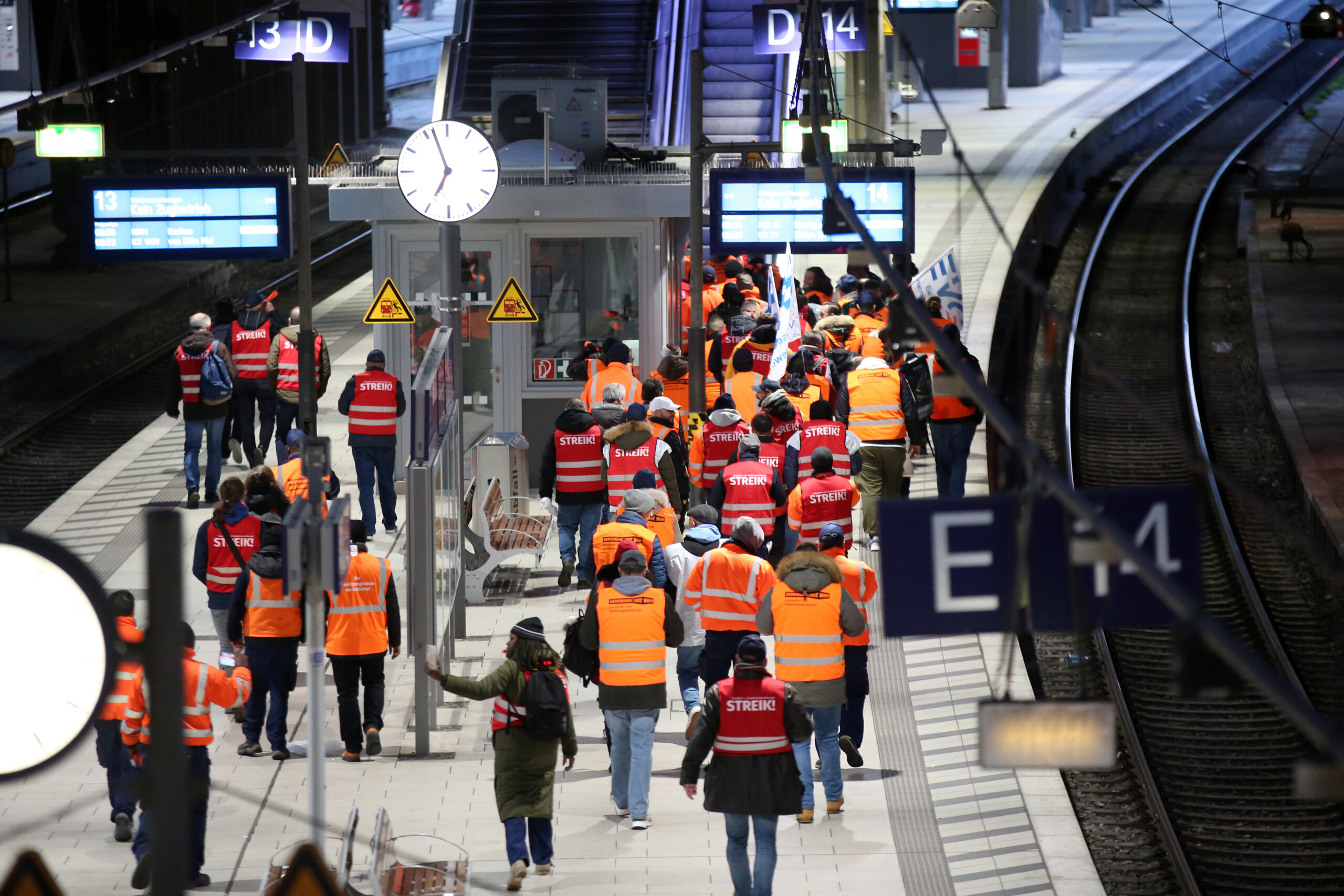 Streikende Mitglieder der EVG ziehen lautstark mit Fahnen und Streikwesten durch den Hamburger Hauptbahnhof.