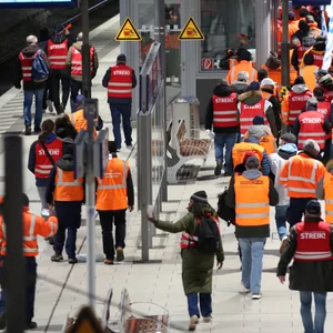 Streikende Mitglieder der EVG ziehen lautstark mit Fahnen und Streikwesten durch den Hamburger Hauptbahnhof.