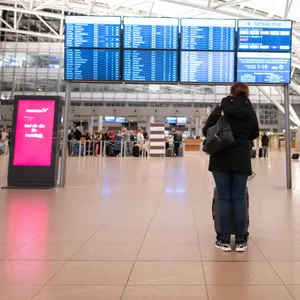 Eine Frau steht am Hamburg Airport vor einer Anzeigetafel. Seit 6 Uhr wird wieder ab Fuhlsbüttel geflogen.