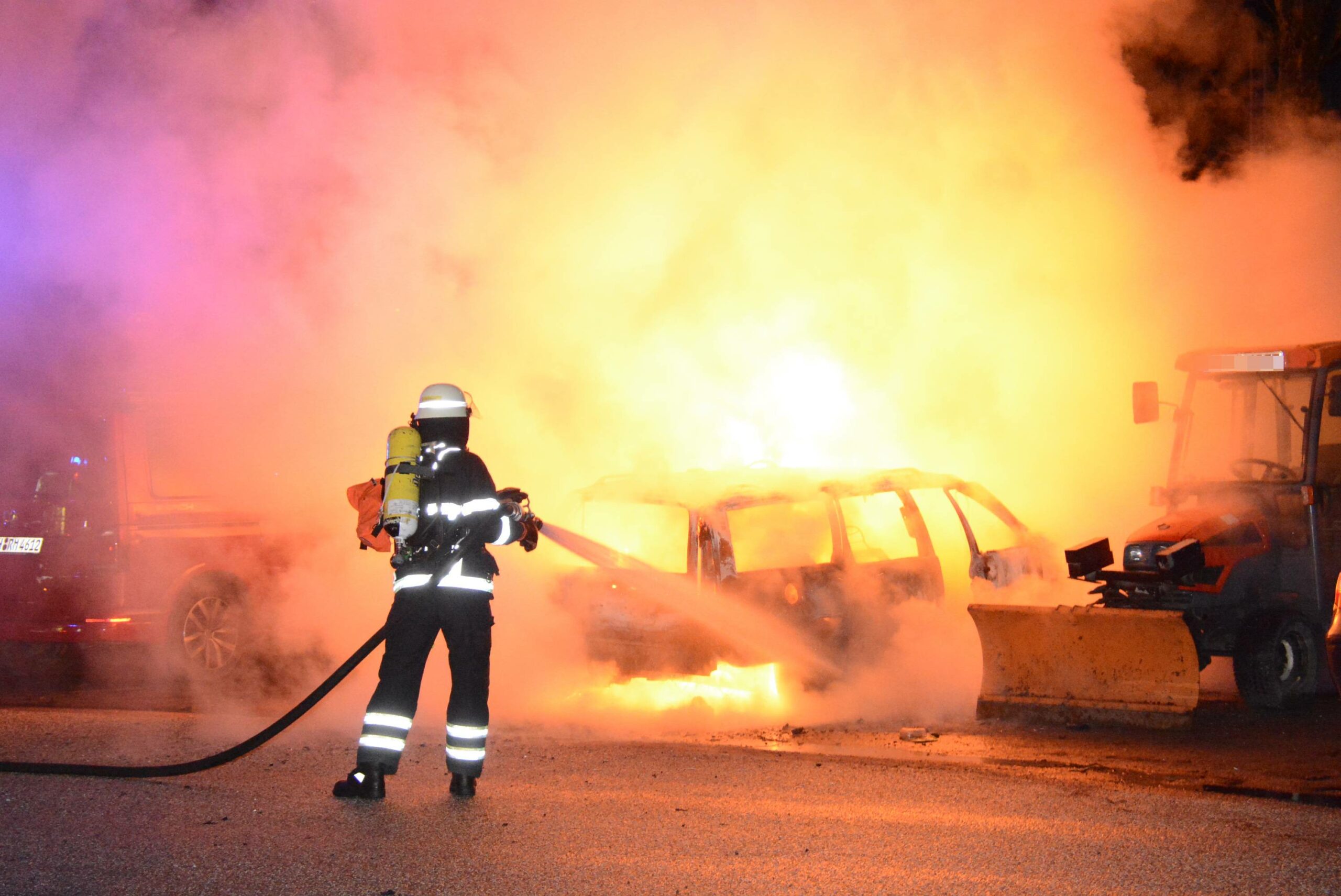 Ein Feuerwehrmann löscht einen brennenden Kombi in Bergedorf.