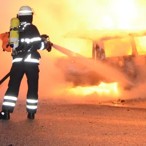 Ein Feuerwehrmann löscht einen brennenden Kombi in Bergedorf.