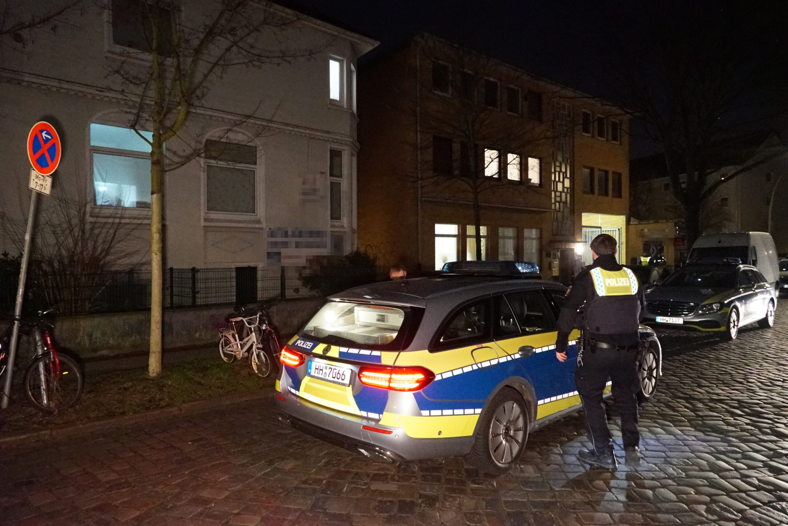 Ein Polizist steht neben einem Polizeiauto vor einem Haus in Hamburg-Barmbek