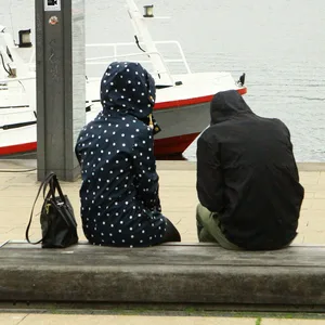 Frau und Mann sitzen bei Hamburger Schmuddelwetter auf einer Bank am Jungfernstieg