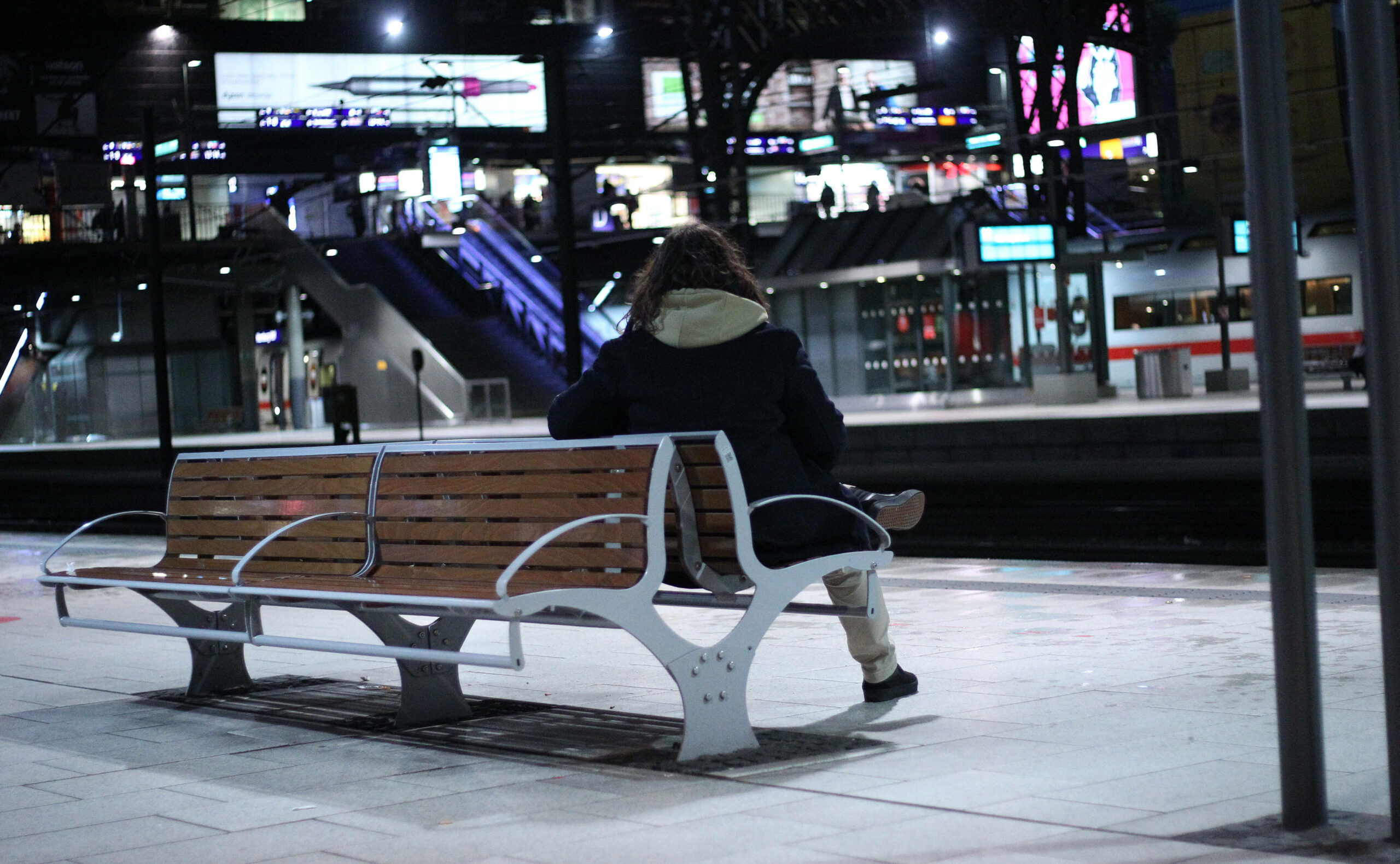 Ein Mann sitzt allein auf einer Bank auf einem ansonsten menschenleeren Bahnsteig am Hauptbahnhof Hamburg.