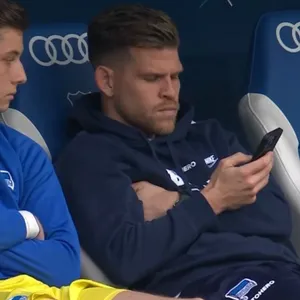 Florian Niederlechner mit dem Handy auf der Ersatzbank