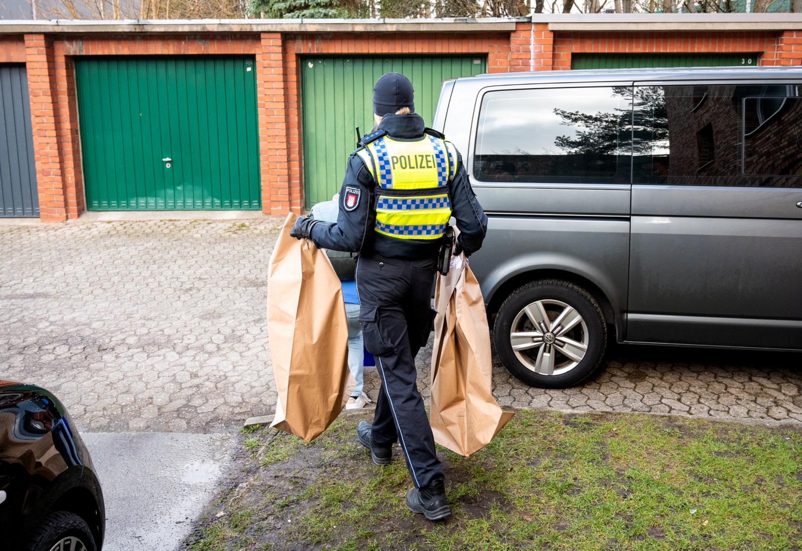 Eine Polizistin mit zwei braunen Säcken, in denen mutmaßliches Beweismittel ist.