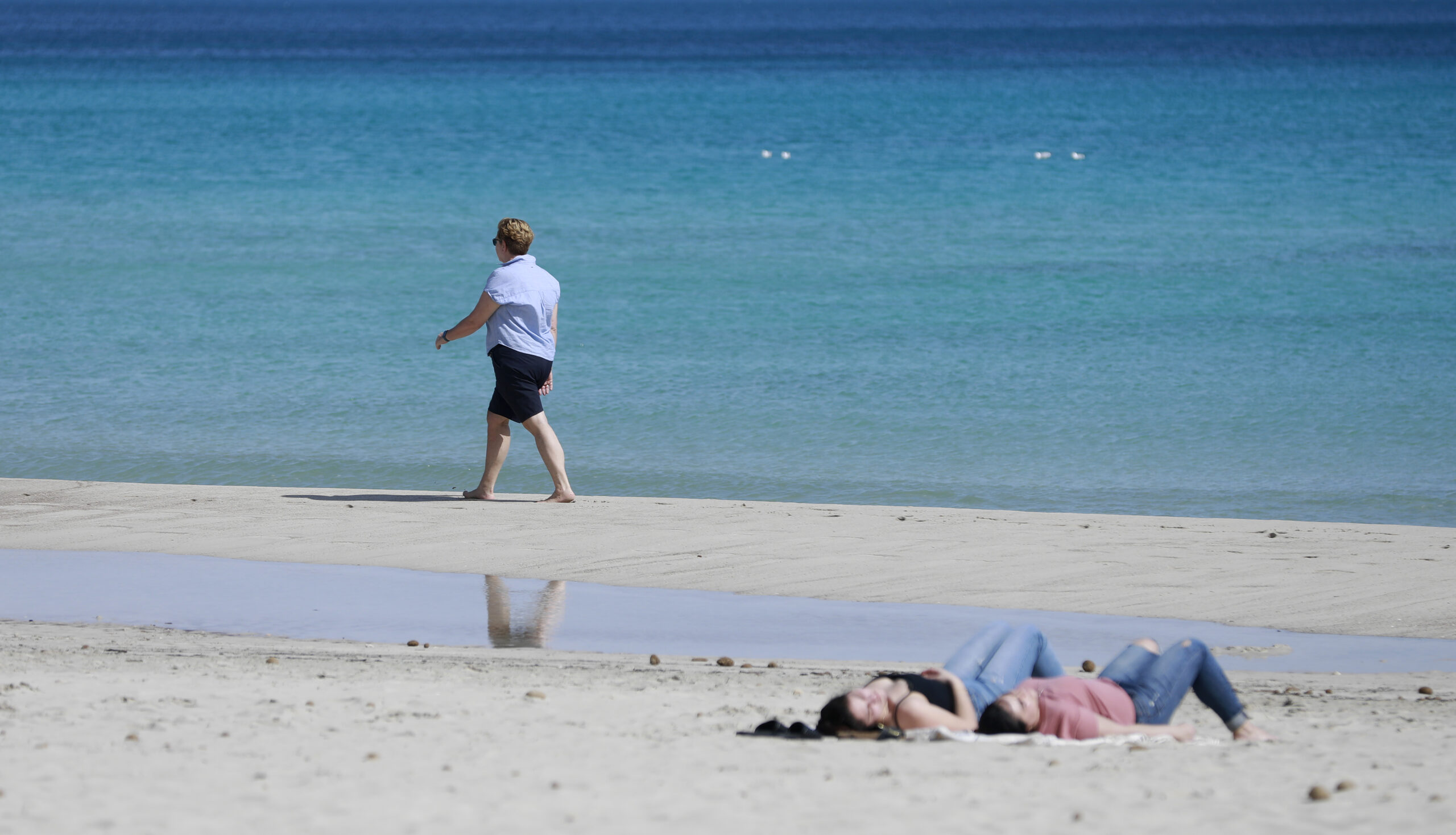 Eine Frau spaziert am Strand von Cala Millor auf Mallorca.