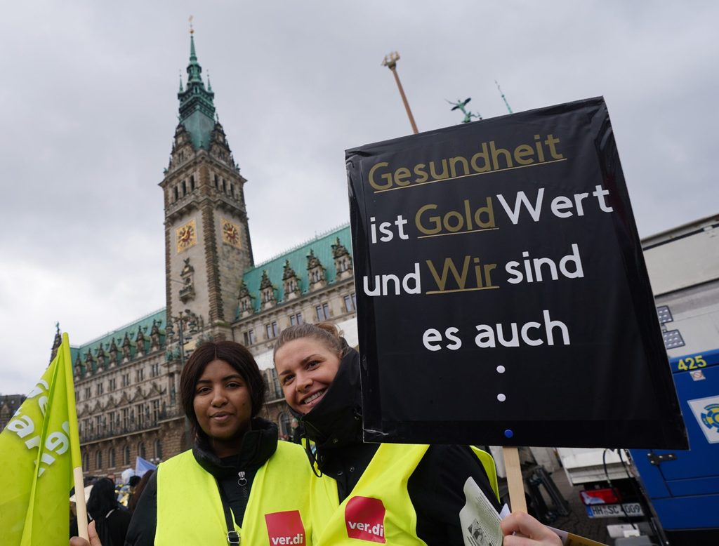 Zwei Streikende präsentieren auf dem Rathausmarkt ihr Plakat.