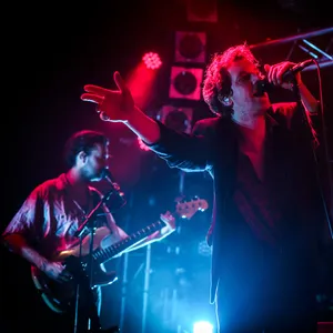 Vorne Devoldere im roten Bühnenlicht, im Hintergrund zwei Musiker