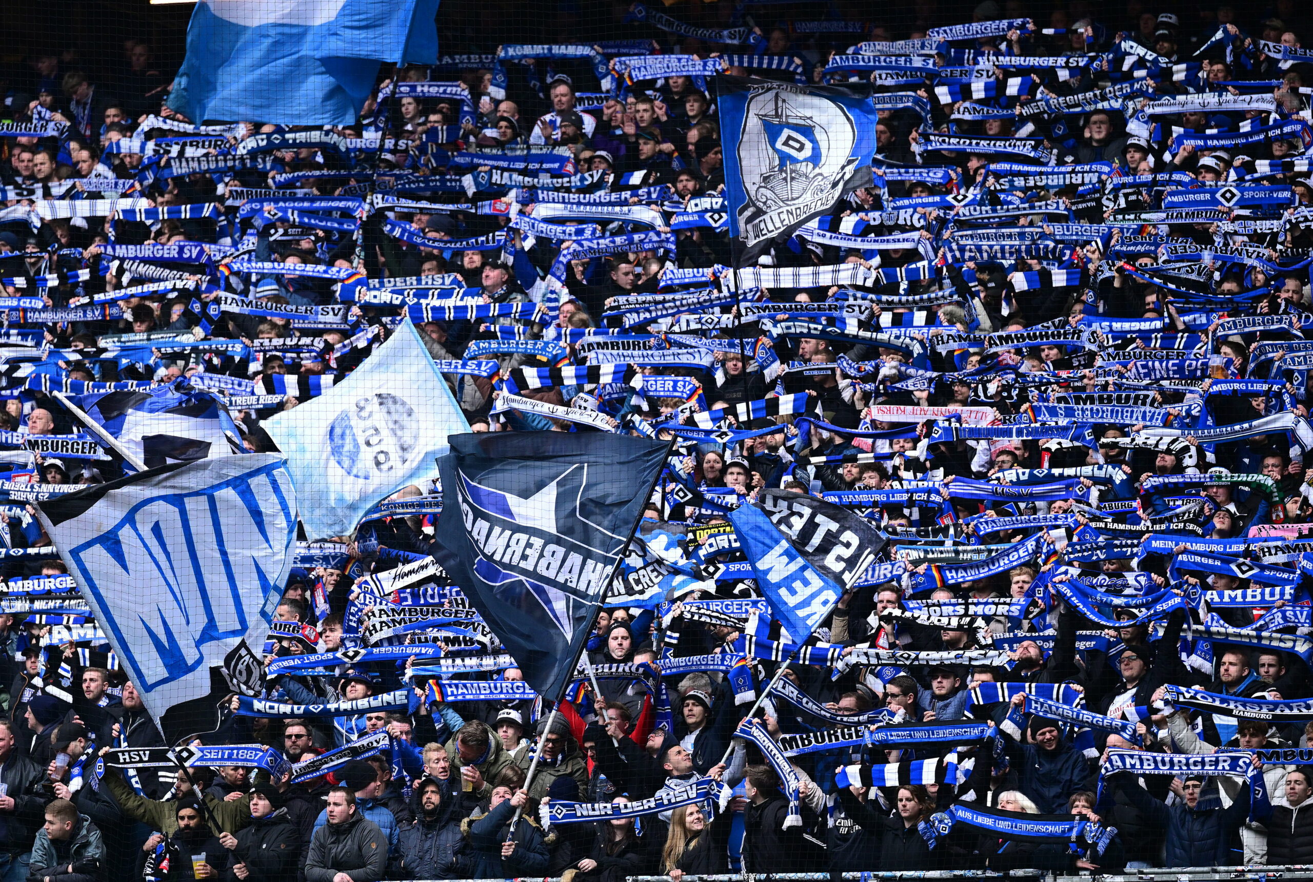 HSV-Fans halten auf der Nordtribüne ihre Schals hoch.