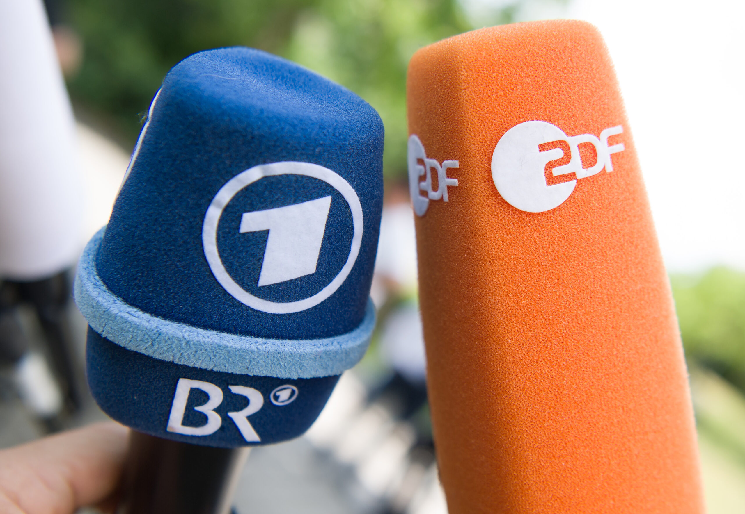 Fernsehmikrofone mit den Logos von ARD/BR und ZDF werden vor Beginn einer Pressekonferenz nebeneinander gehalten.