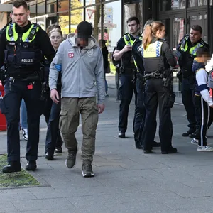 Der verdächtige Taschendieb wird von Polizisten abgeführt.