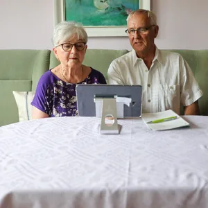 Ein Rentnerpaar sitzt in seinem Wohnzimmer vor einem Laptop
