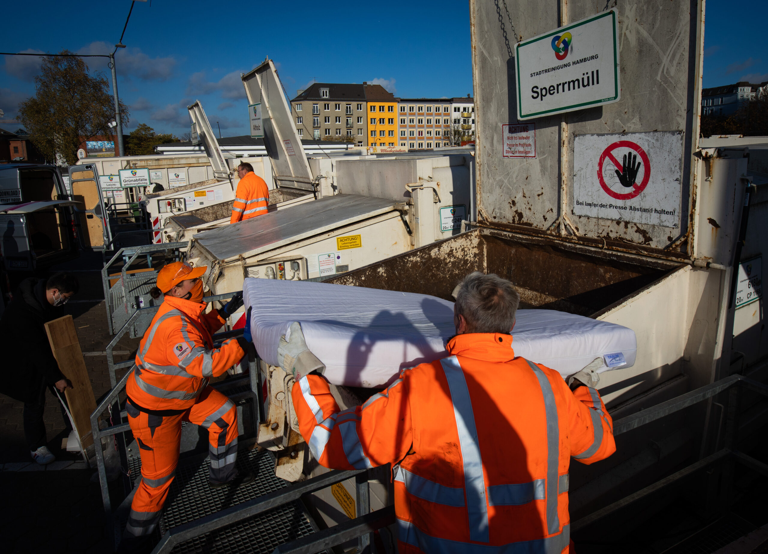 Mitarbeiter der Stadtreinigung werfen eine Matratze in einen Sperrmüllcontainer auf dem Recyclinghof St. Pauli.