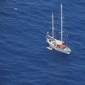 Migranten sitzen mit Rettungswesten in einem Holzboot und auf dem von einem deutschen Verein betriebene Hilfsschiff «Nadir» (l). (Archivbild)
