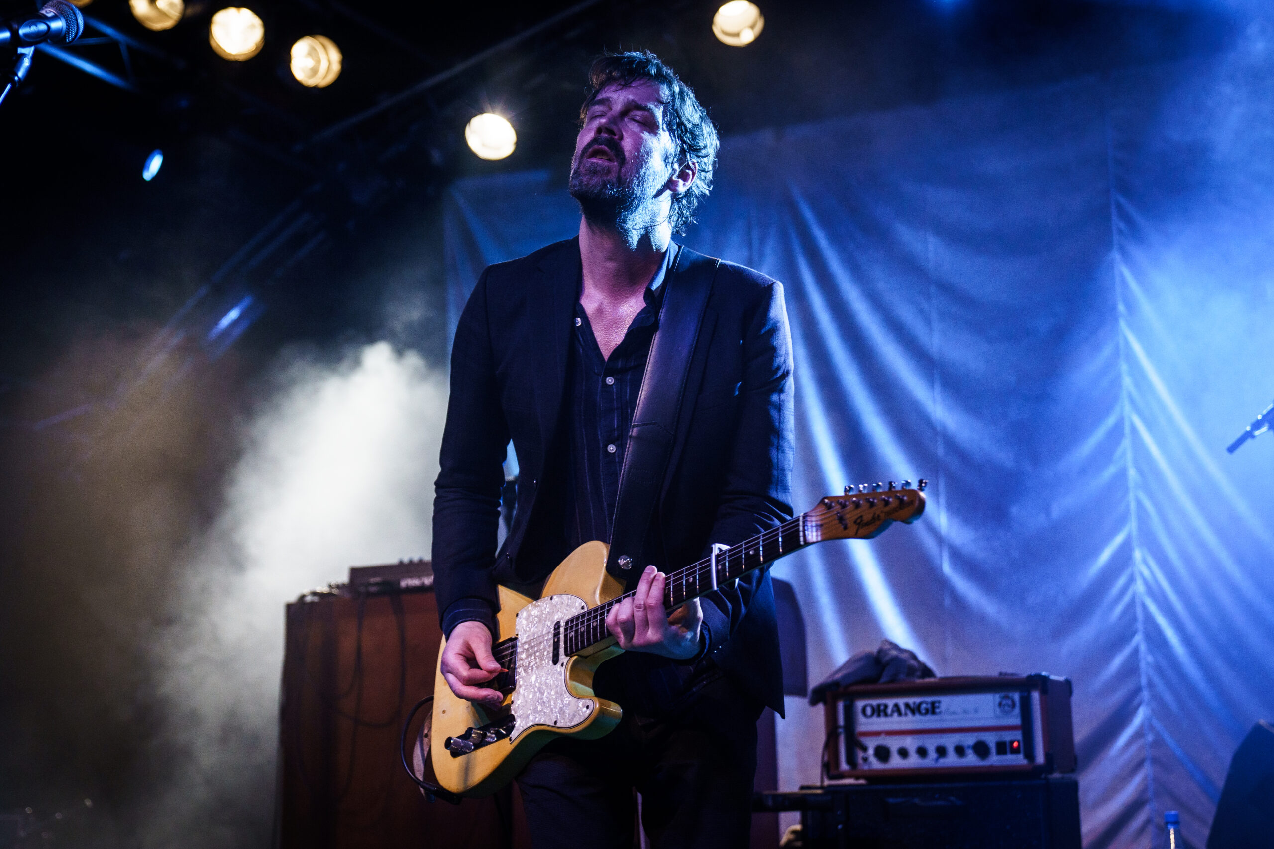 Niels Frevert spielt mit geschlossenen Augen in blauem Bühnenlicht Gitarre