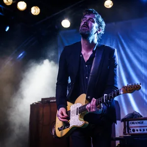 Niels Frevert spielt mit geschlossenen Augen in blauem Bühnenlicht Gitarre