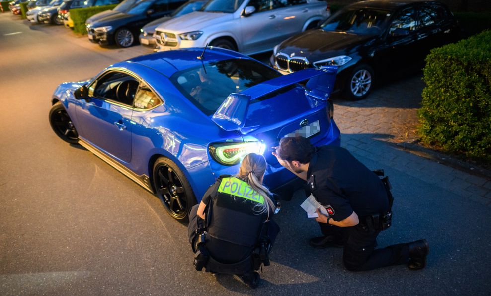 Polizisten kontrollieren ein getuntes Fahrzeug.