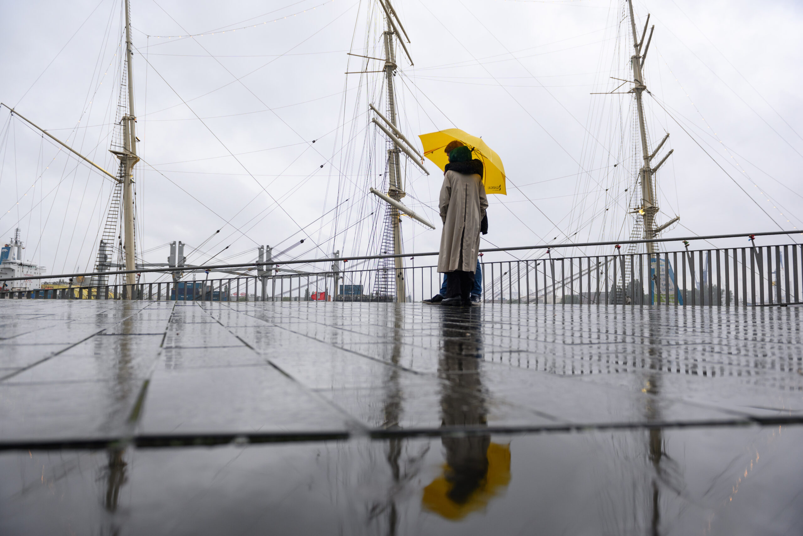 Ein Pärchen steht unter einem Regenschirm auf der Jan-Fedder-Promenade einem Kreuzfahrtschiff.