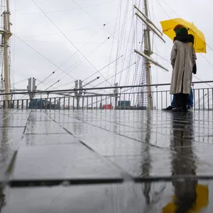 Ein Pärchen steht unter einem Regenschirm auf der Jan-Fedder-Promenade einem Kreuzfahrtschiff.