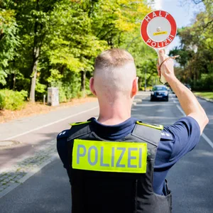 Ein Polizist hält bei einer Verkehrskontrolle ein Auto an. (Symbolbild)