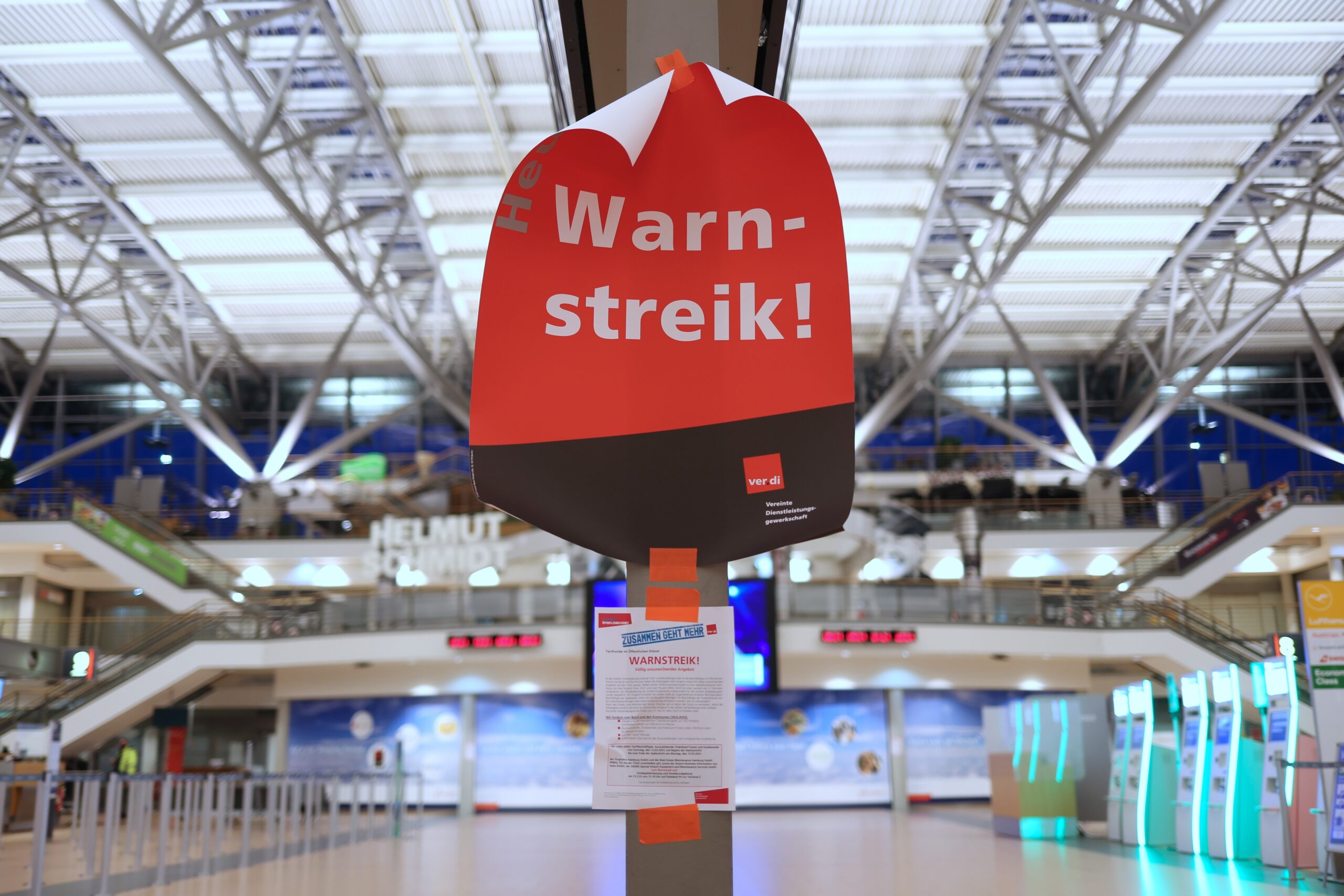 Ein Plakat mit dem Text „Warnstreik!“ hängt im menschenleeren Terminal 2 im Flughafen Hamburg.