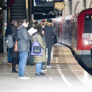 Reisende warten am Hauptbahnhof auf eine einfahrende S-Bahn.