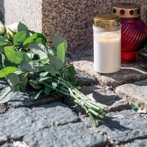 Blumen und Grablichter auf dem Gehweg.