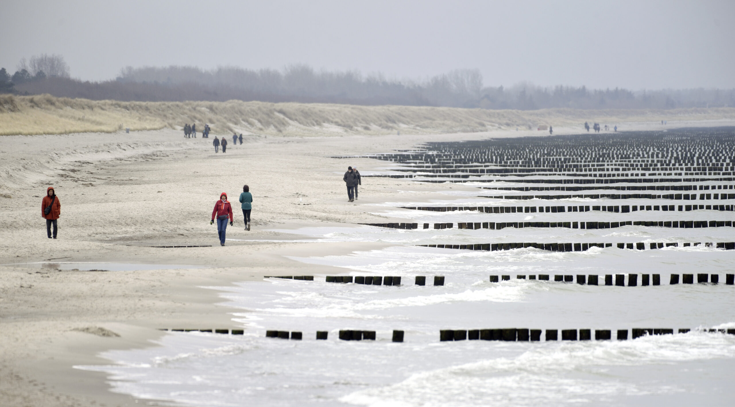Vereinzelte Spaziergänger laufen am Strand vom Ostseebad Wustrow auf dem Darss.