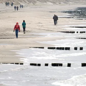 Vereinzelte Spaziergänger laufen am Strand vom Ostseebad Wustrow auf dem Darss.