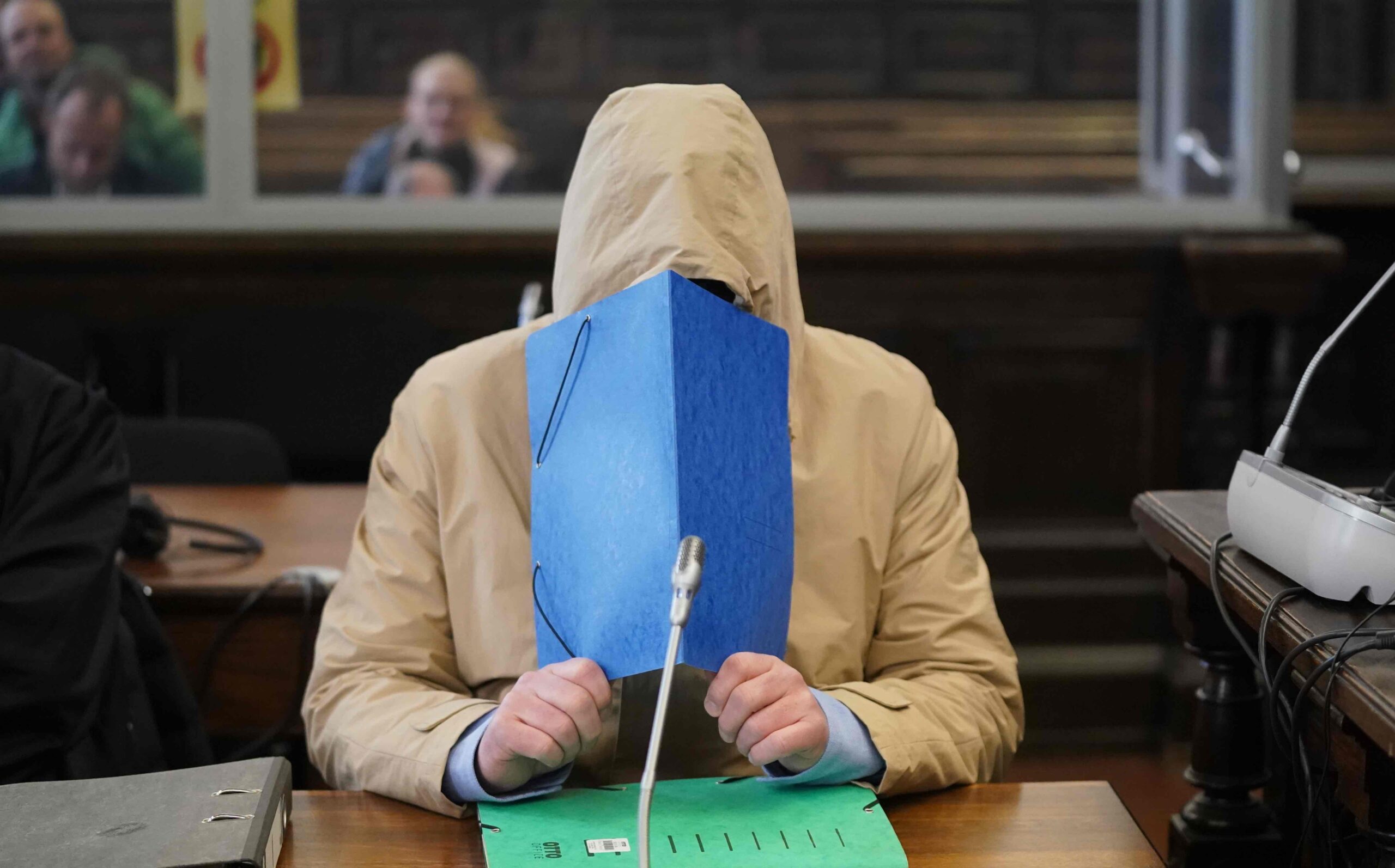 Im Gerichtssaal versteckt sich Michael Osterburg hinter einer blauen Mappe. (Archivbild)