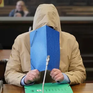 Im Gerichtssaal versteckt sich Michael Osterburg hinter einer blauen Mappe. (Archivbild)