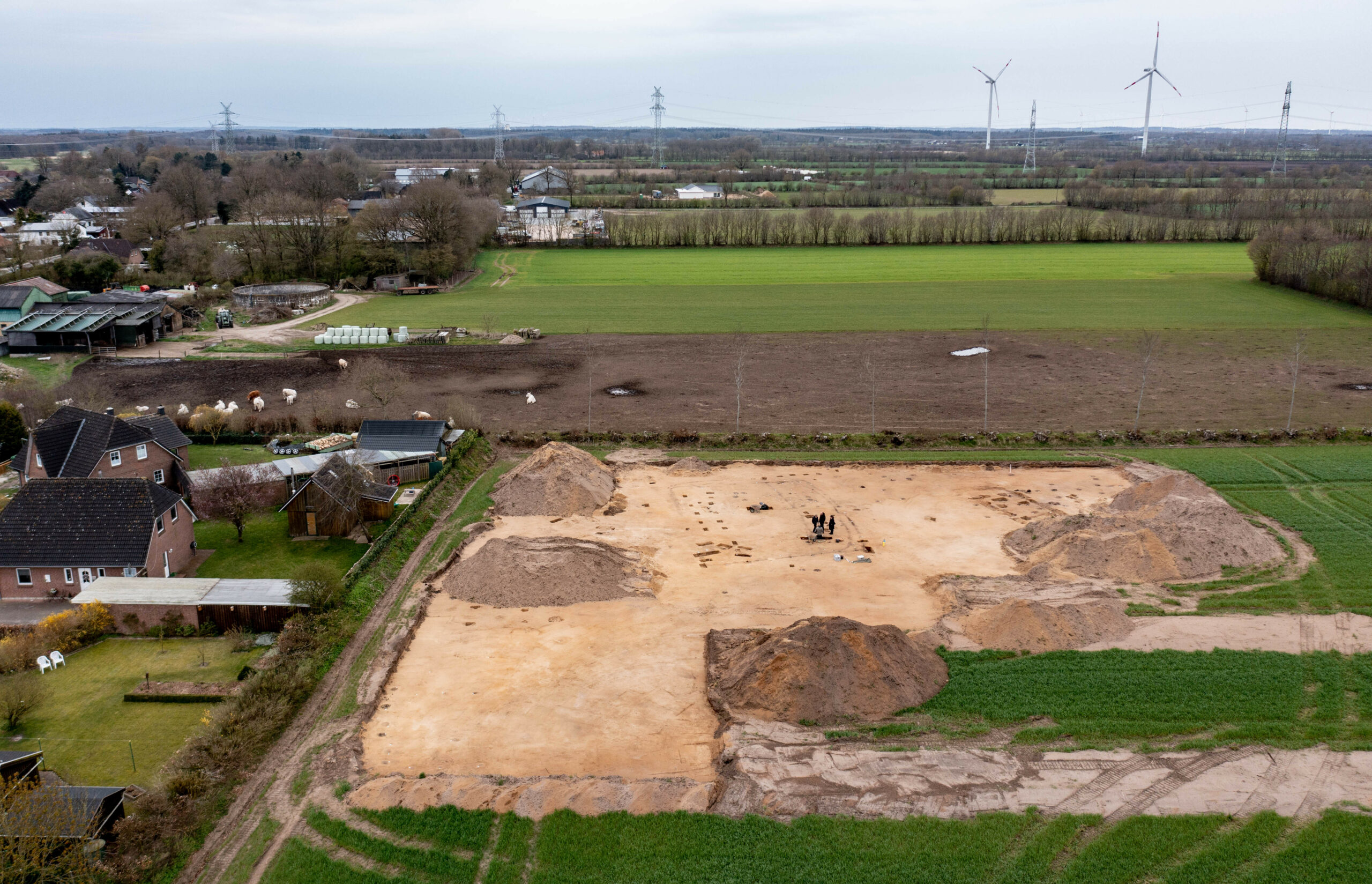 Archäologen graben in einem Feld innerhalb der Umrisse eines Gehöfts aus der römischen Kaiserzeit.