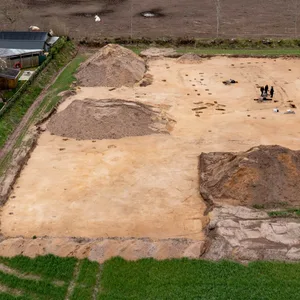 Archäologen graben in einem Feld innerhalb der Umrisse eines Gehöfts aus der römischen Kaiserzeit.