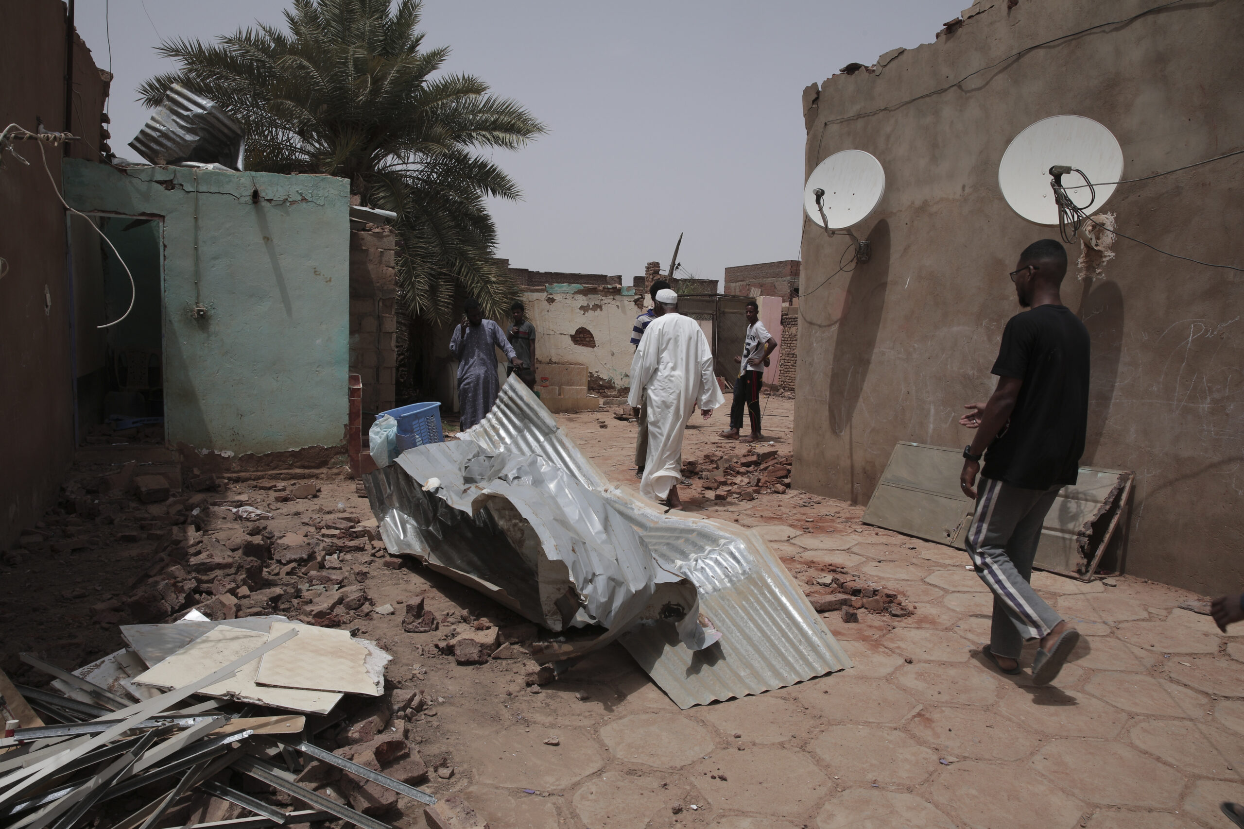Menschen gehen an einem Haus vorbei, das bei den jüngsten Kämpfen beschädigt wurde. Im Sudan sind vor mehr als einer Woche schwere Kämpfe zwischen dem Militär und Paramilitär ausgebrochen.