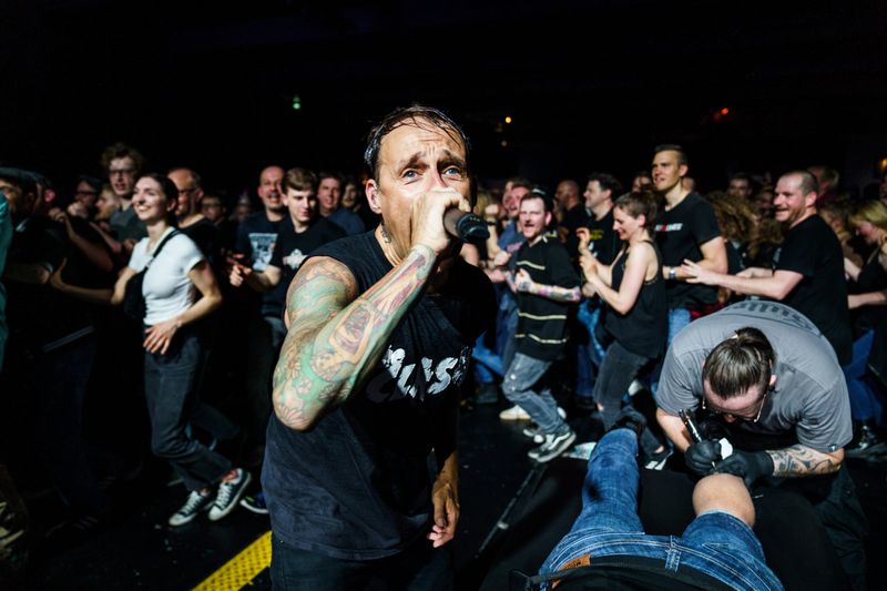 Donots-Frontmann Ingo Knollmann steht in Hamburg im Circle-Pit. Neben ihm wird ein Fan tätowiert.